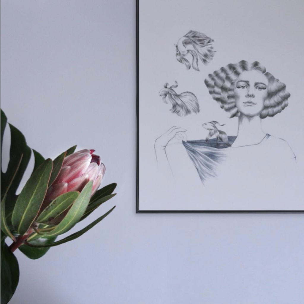 Mermaid artprint von youdesignme an der Wand mit Blume im Vordergrund