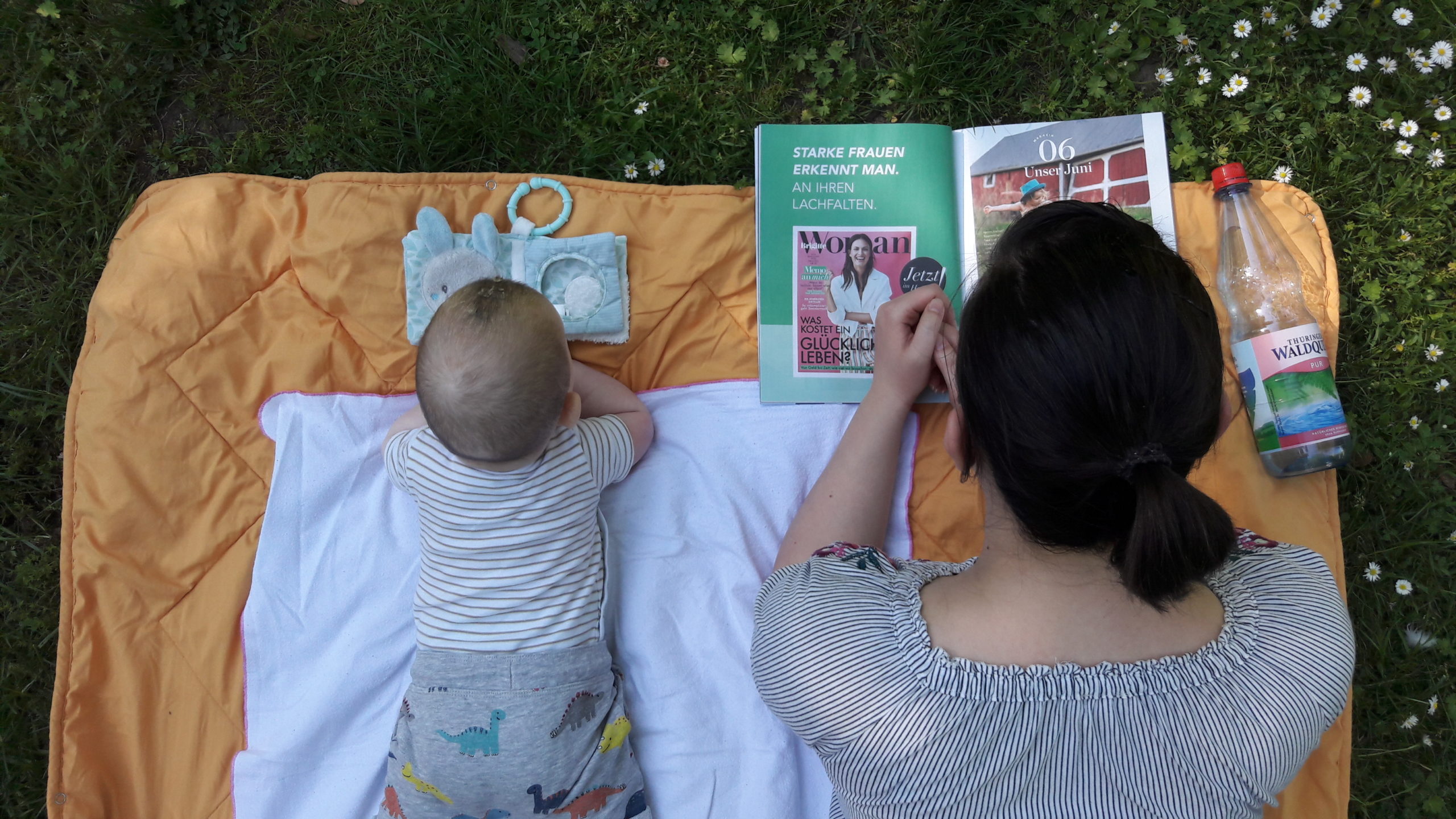 Mutter und Sohn liegen auf dem Bauch auf einer Decke im Park und lesen