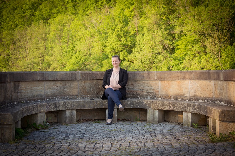 Julia sitzt in einem der Bögen auf der Werrabrücke bei Creuzburg und schaut in die Kamera.